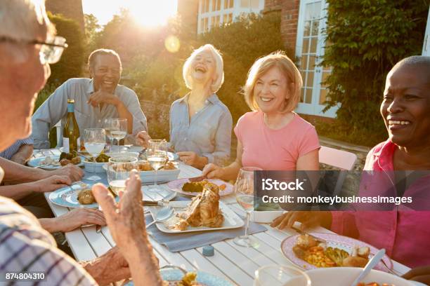 Group Of Senior Friends Enjoying Outdoor Dinner Party At Home Stock Photo - Download Image Now