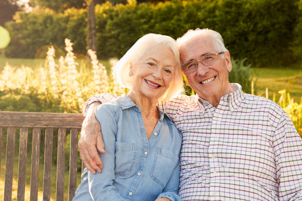senior couple assis sur un banc de jardin en soirée soleil - octogénaire et plus photos et images de collection
