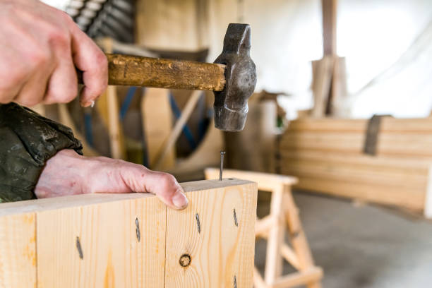istock Close up man hammers nail in wooden beam 874809286