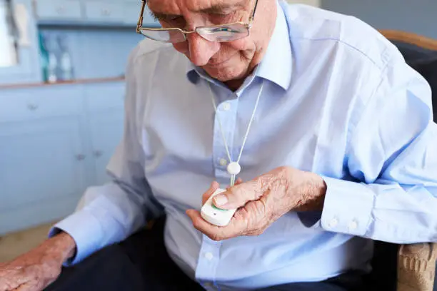 Senior Man At Home Using Distress Alarm Call Button