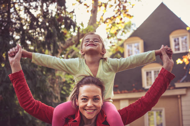istock Mother carrying daughter on piggyback. 874814696