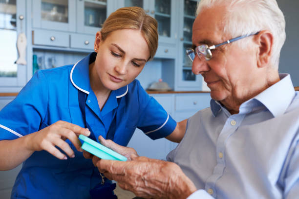 Nurse Helping Senior Man To Organize Medication On Home Visit