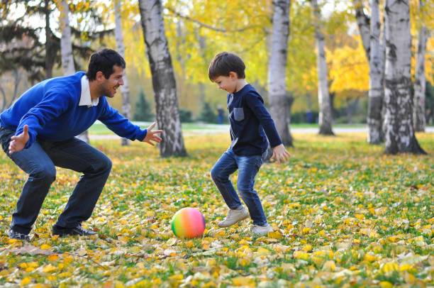 istock Father and son play with ball in autumn park. 874815208
