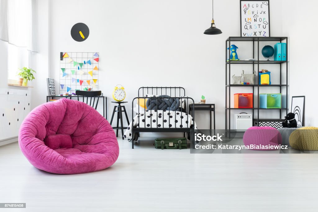 Pink pouf in kid's room Pink pouf and toys in scandi kid's room with knot pillow on bed with patterned bedsheets Child Stock Photo