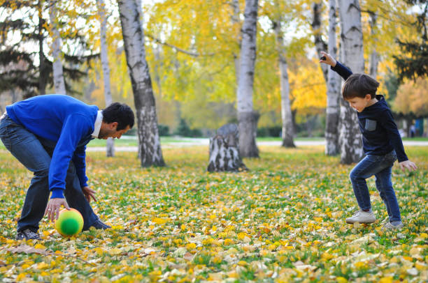 istock Father and son play with ball in autumn park. 874815764