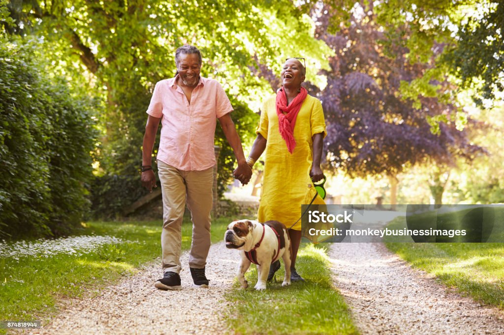 Senior Couple Walking With Pet Bulldog In Countryside Senior Adult Stock Photo