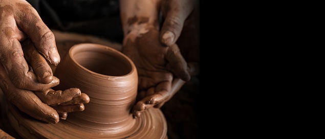 Hands of potter making clay pot, closeup photo
