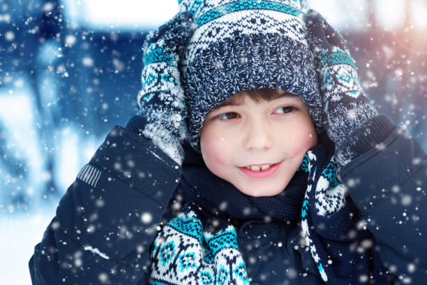 istock Boy in knitted hat, gloves and scarf outdoors at snowfall 874822322