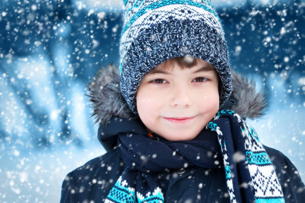 istock Boy in knitted hat, gloves and scarf outdoors at snowfall 874822348