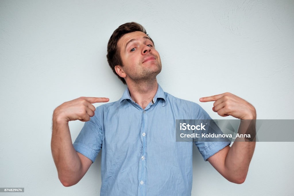 Self-satisfied and proud caucasian young man looks forward Self-satisfied and proud caucasian young man looks forward showing with index fingers on himself Vanity Stock Photo