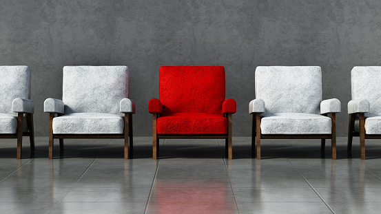 Red chair standing out among white chairs in a room.