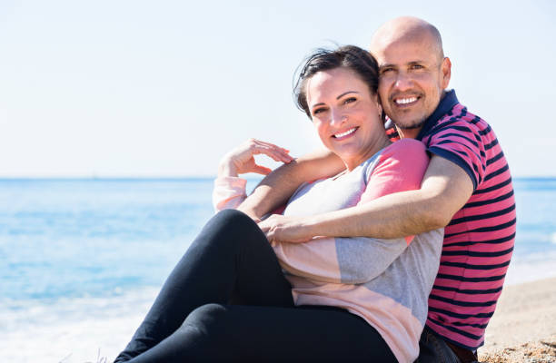 istock Couple gladly hugging each other and enjoying the beach 874840298