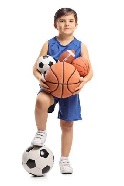 Photo of Little boy holding different kinds of sports balls