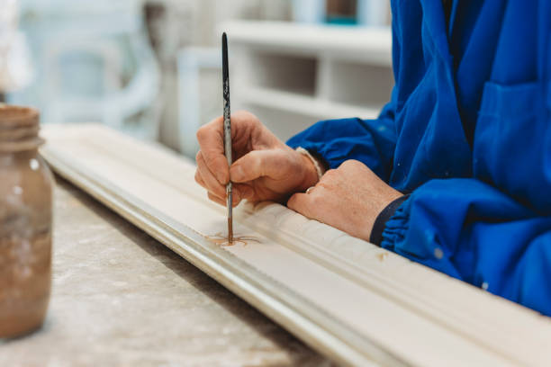 istock Craftsman carpenter painting a frame with brush 874856304