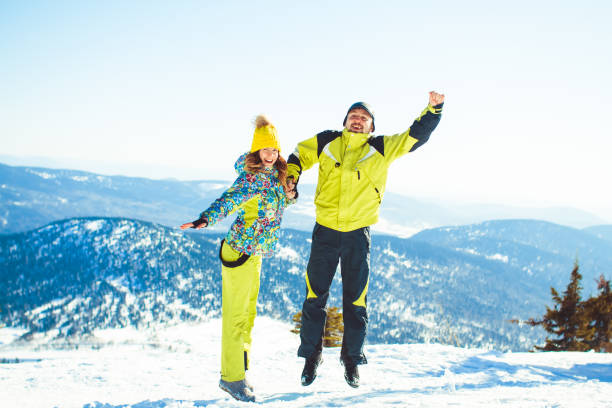 casal pulando no inverno nas montanhas - chearful - fotografias e filmes do acervo