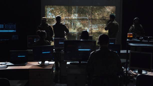 Group of people in dark room launching a missle Group of soldiers or spies in dark room with large monitors and advanced satellite communication technology launching a missle. Includes flashing yellow light. air force stock pictures, royalty-free photos & images