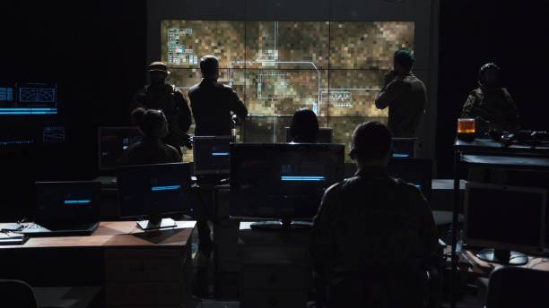 Group of people in dark room launching a missle Group of soldiers or spies in dark room with large monitors and advanced satellite communication technology launching a missle. Includes flashing yellow light. military building photos stock pictures, royalty-free photos & images