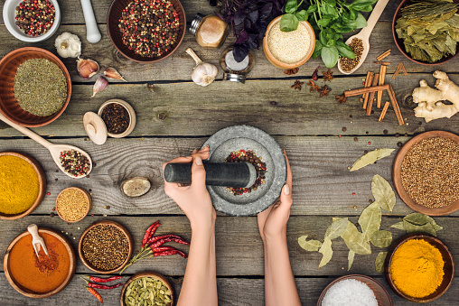 Cropped image of woman grinding pepper with granitic pestle and mortar
