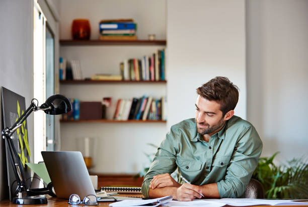 Cropped shot of a handsome young man making notes while working at home