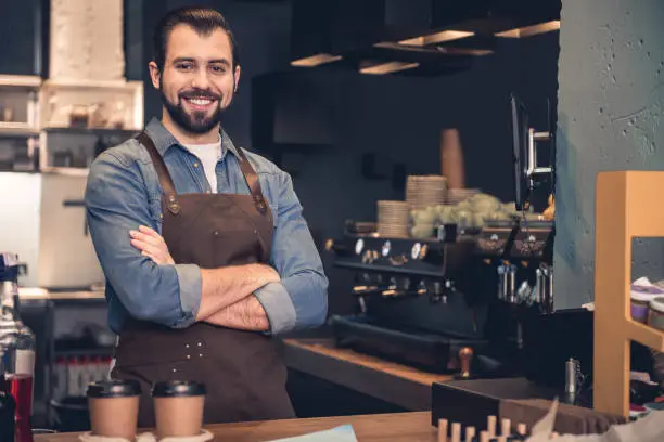 Portrait of smiling man situating at table while having job in confectionary shop. Occupation concept. Copy space