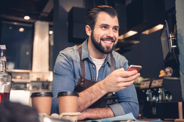 istock Happy barista keeping phone in hand 874875596