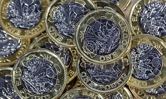 One pound coins in a pile - directly overhead in a horizontal format