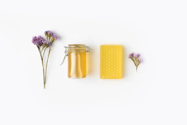 top view of handcrafted honey soap with jar and lavander flowers on white surface