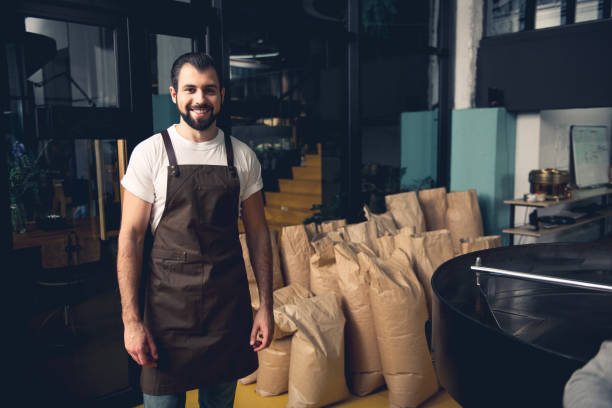 istock Smile coffee roaster worker standing near bags 874889368
