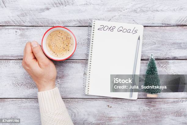 Taza De Café Y Notebook Con Goles De Asimiento De La Mano Masculina Para 2018 Planificación Y La Motivación Para El Concepto De Año Nuevo Foto de stock y más banco de imágenes de 2018