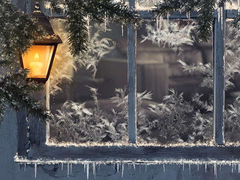 Beautiful winter window. Snow, icicles. Yellow lantern