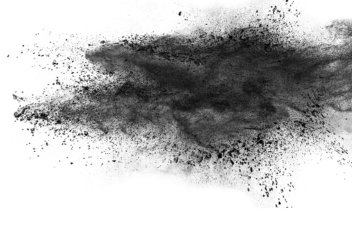 Black powder explosion against white background.The particles of charcoal splatted on white background. Closeup of black dust particles explode isolated on white background.