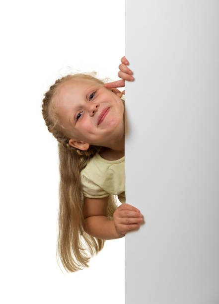 istock Little laughing girl peeking out from behind an empty banner, isolated on white 874899700