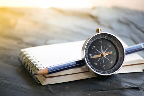 Photo of Notepad with compass wood background. Using wallpaper or background travel or navigator image.