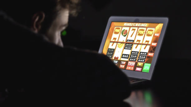 밤에 랩톱 컴퓨터에 온라인 카지노 슬롯 머신 앞에서 안경 도박 중독된 남자와 - gambling 뉴스 사진 이미지