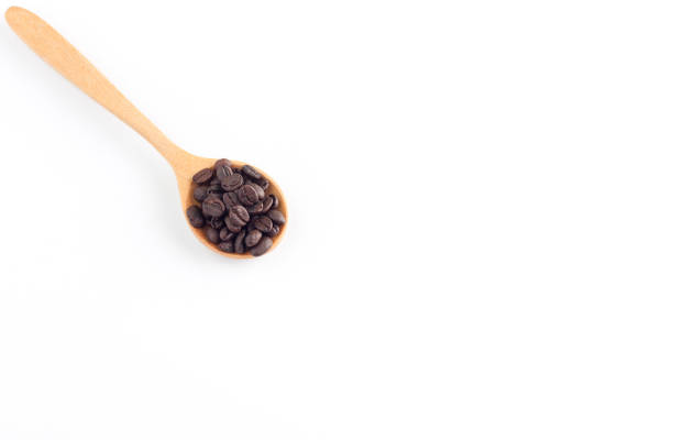 istock Coffee seeds in wooden spoon on white background 874915374