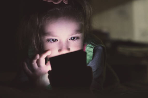 little girl with smartphone lying in a bed, - sleeping child bedtime little girls imagens e fotografias de stock