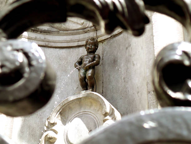 Bronze Sculpture of Manneken Pis as View Through the Iron Fence, a Small but Famous Landmark of Brussels of Belgium Bronze Sculpture of Manneken Pis as View Through the Iron Fence, a Small but Famous Landmark of Brussels of Belgium manneken pis statue in brussels belgium stock pictures, royalty-free photos & images