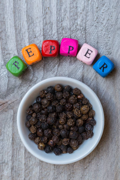istock Pepper in bowl with letter cube on wooden background 874919760