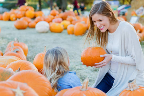 istock Attentive mother enjoys pumpkin patch with young daughter 874922934