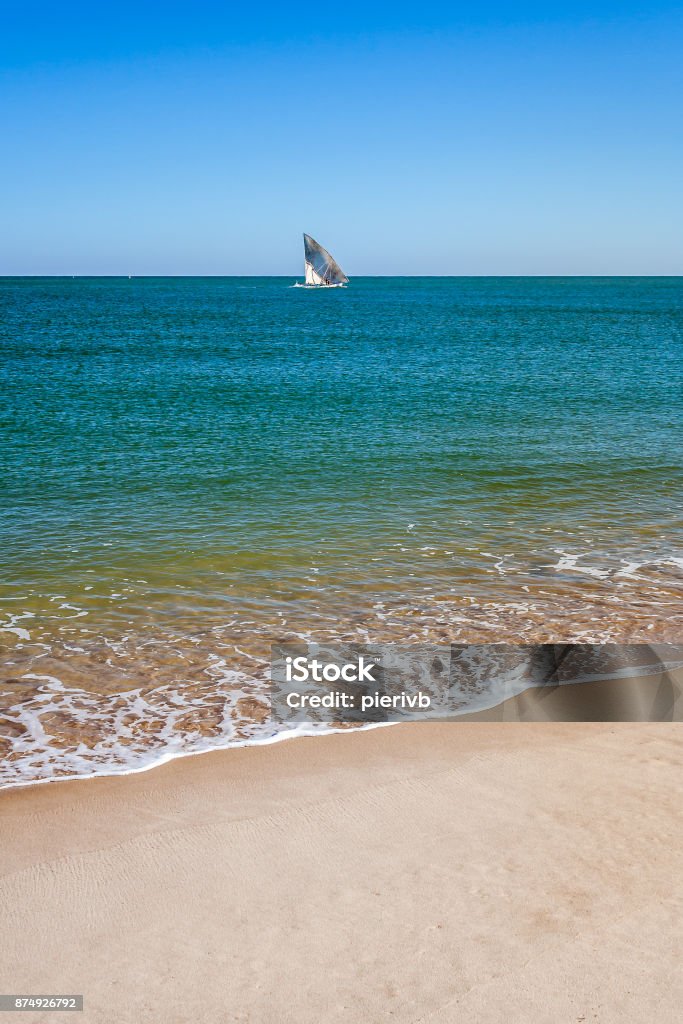 Wave on the beach Wave on the beach of western Madagascar with a sailboat in the distance Africa Stock Photo