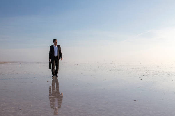 istock Man in black suit on salt lake 874927392