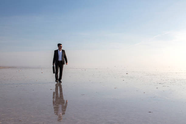istock Man in black suit on salt lake 874927394