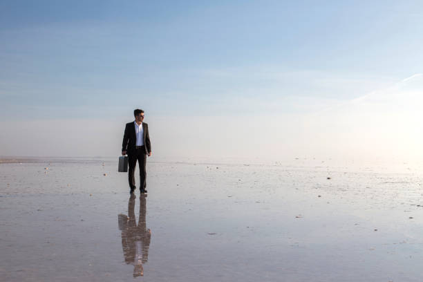 istock Man in black suit on salt lake 874927396