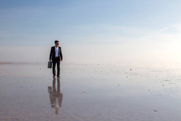 istock Man in black suit on salt lake 874927398