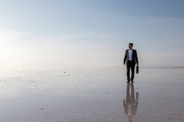 istock Man in black suit on salt lake 874927402