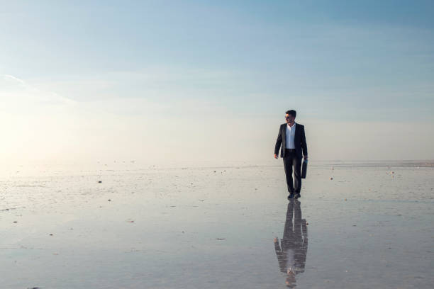 istock Man in black suit on salt lake 874927406
