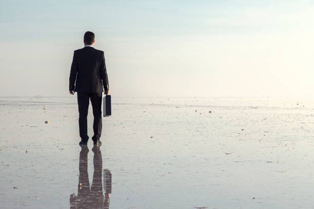 istock Man in black suit on salt lake 874927646