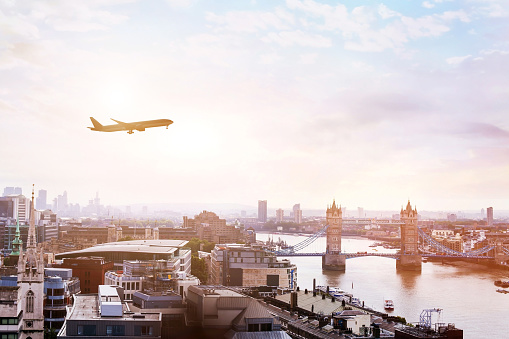 travel to London by flight, airplane in the sky over Tower Bridge