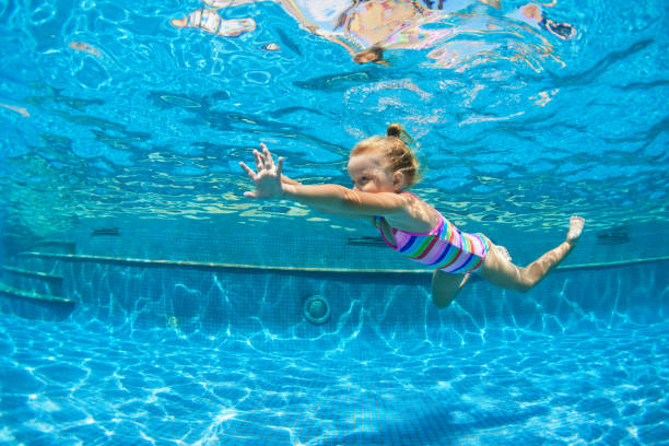 Child jump underwater into swimming pool Funny portrait of child learn swimming, diving in blue pool with fun - jumping deep down underwater with splashes. Healthy family lifestyle, kids water sports activity, swimming lesson with parents. raro stock pictures, royalty-free photos & images