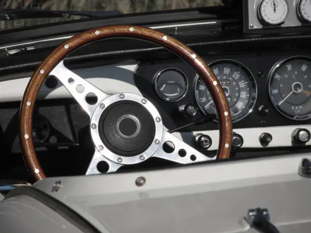 Photo of Dashboard of an old british classic car . Particular view of steering wheel and vehicle instrument panel . The car is a Triumph TR3 model produced between 1955 and 1962
